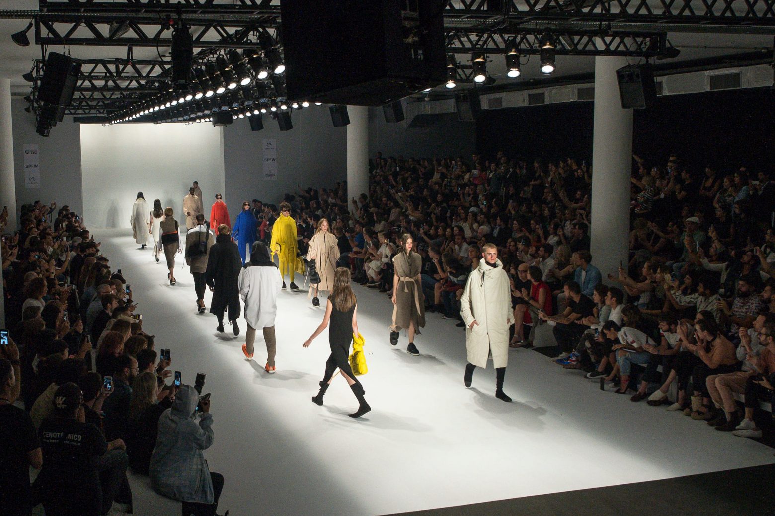 Público tirando fotos e pessoas desfilando no São Paulo Fashion Week.