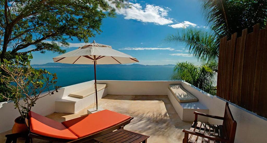 Vista do mar, varanda com espreguiçadeira e guarda sol. Resort Refúgio do Estaleiro - Porto Belo