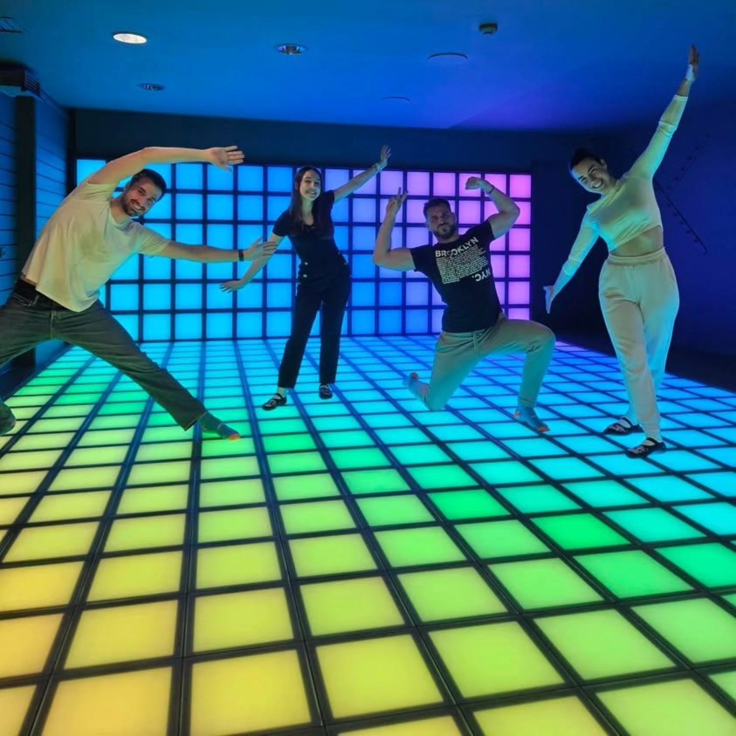 Banzai - sala com luzes colorida, quatro pessoas pulando