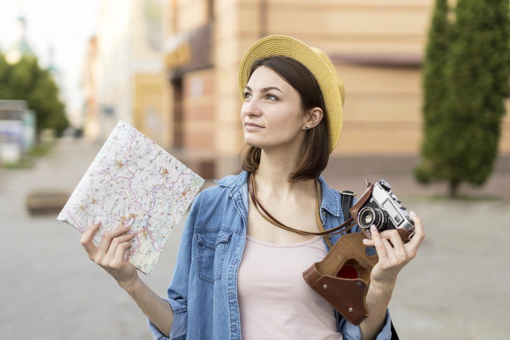 Banco de imagens. Mulher com mapa e câmera fotográfica na mão.