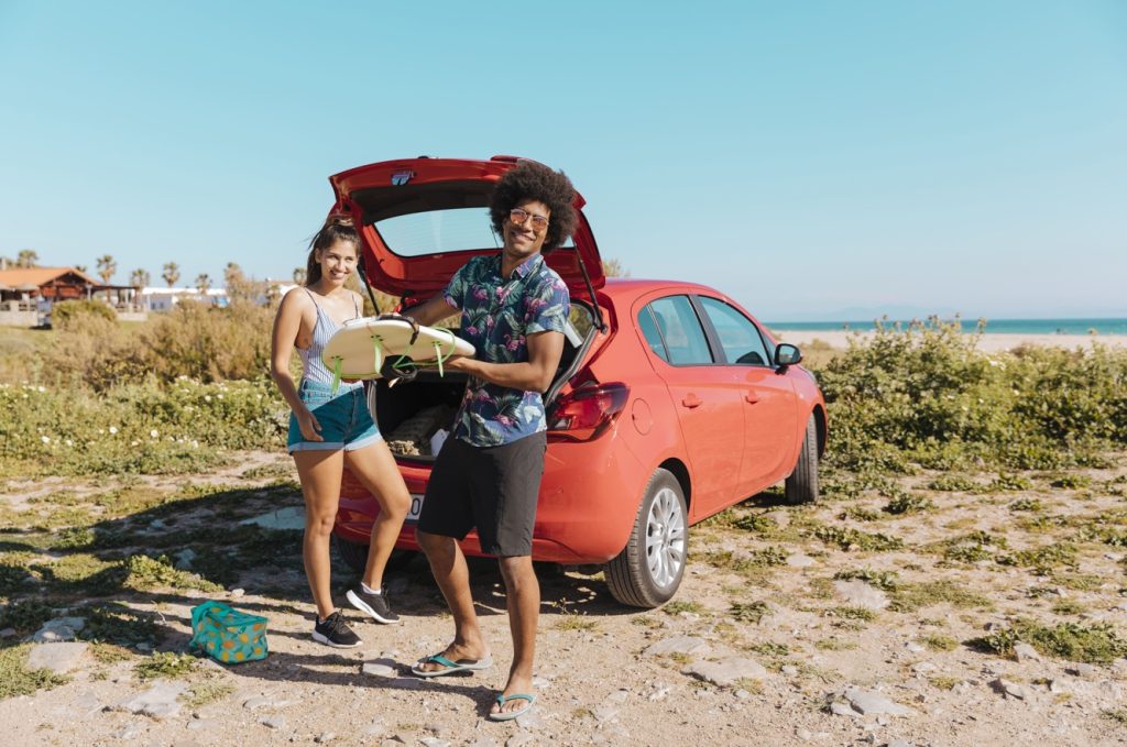 Banco de imagens. Carro vermelho e casal. Praia.