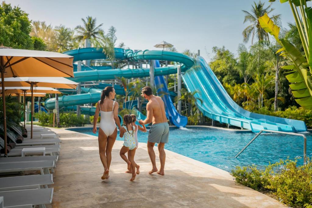 Família andando na frente do toboágua e piscina. Resort Punta Cana.