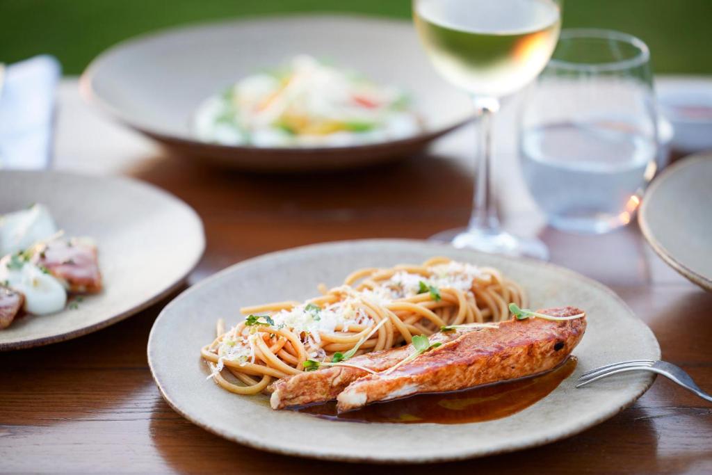 Prato de salmão e macarrão, taça de vinho branco