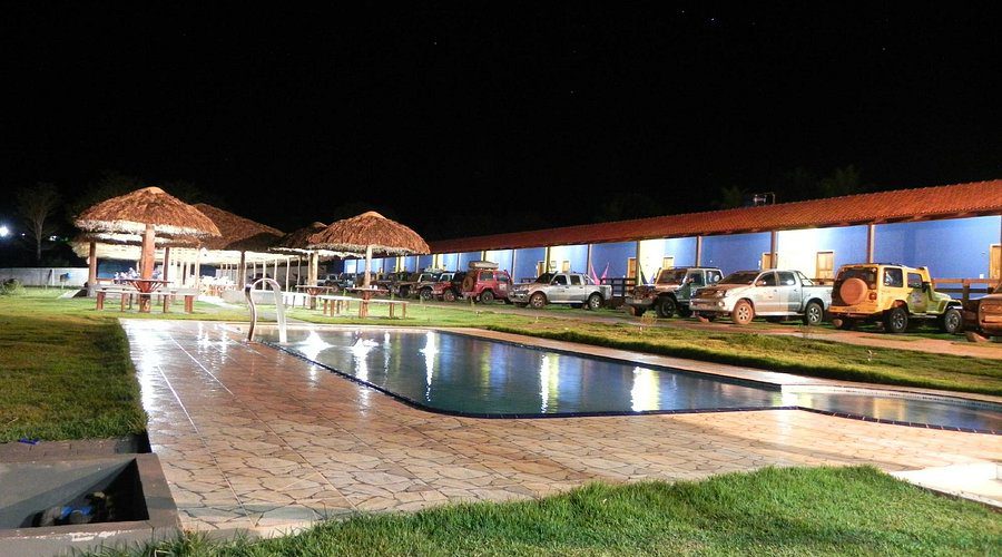 Pousada Santa Helena, situada em Mateiros. Imagem com vista para a piscina a noite, rodeada de carros 4x4  e entrada dos quartos