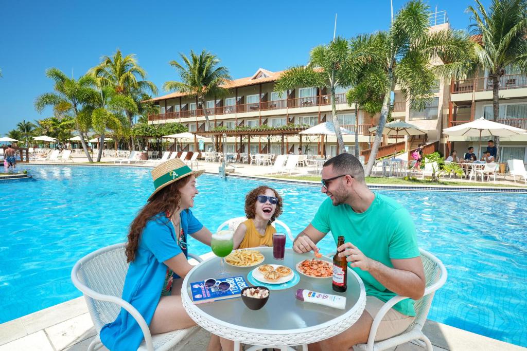 família sentada na beira da piscina comendo