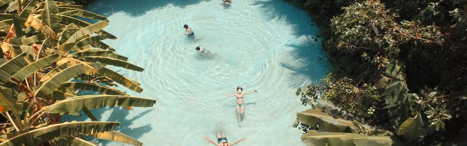Imagem panorâmica de um fervedouro de água azul cristalina com pessoas nadando