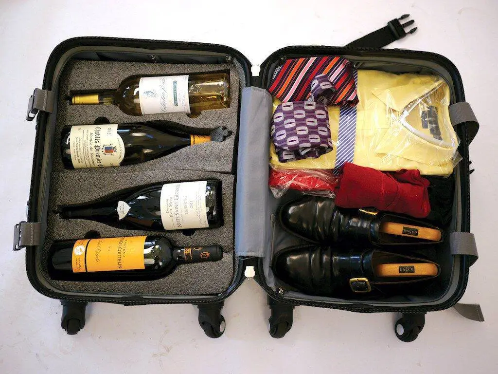 Garrafas de vinho dentro de uma mala aberta de viagem.