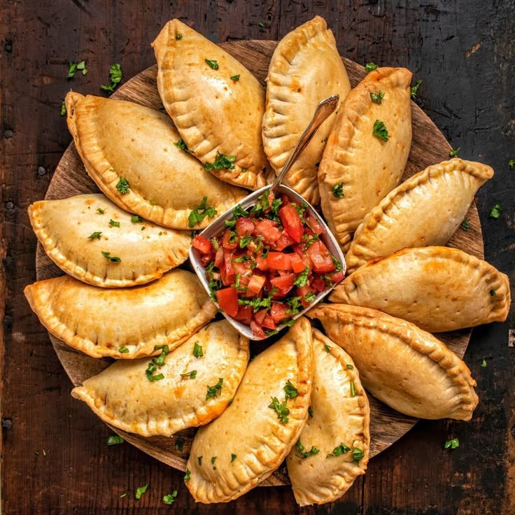 Uma foto de várias empanadas ao redor de um prato com tomates.