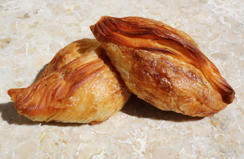 Uma foto de dois Pastizzi, um salgado tradicional maltês.